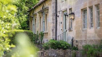 A stone building with multiple windows and a stone wall.