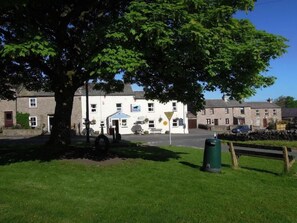 A building with a white facade, a bench, and a tree in the foreground.