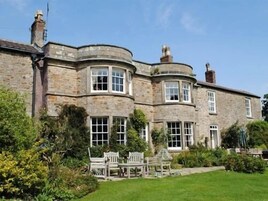 A stone building with multiple windows and a lawn in front.