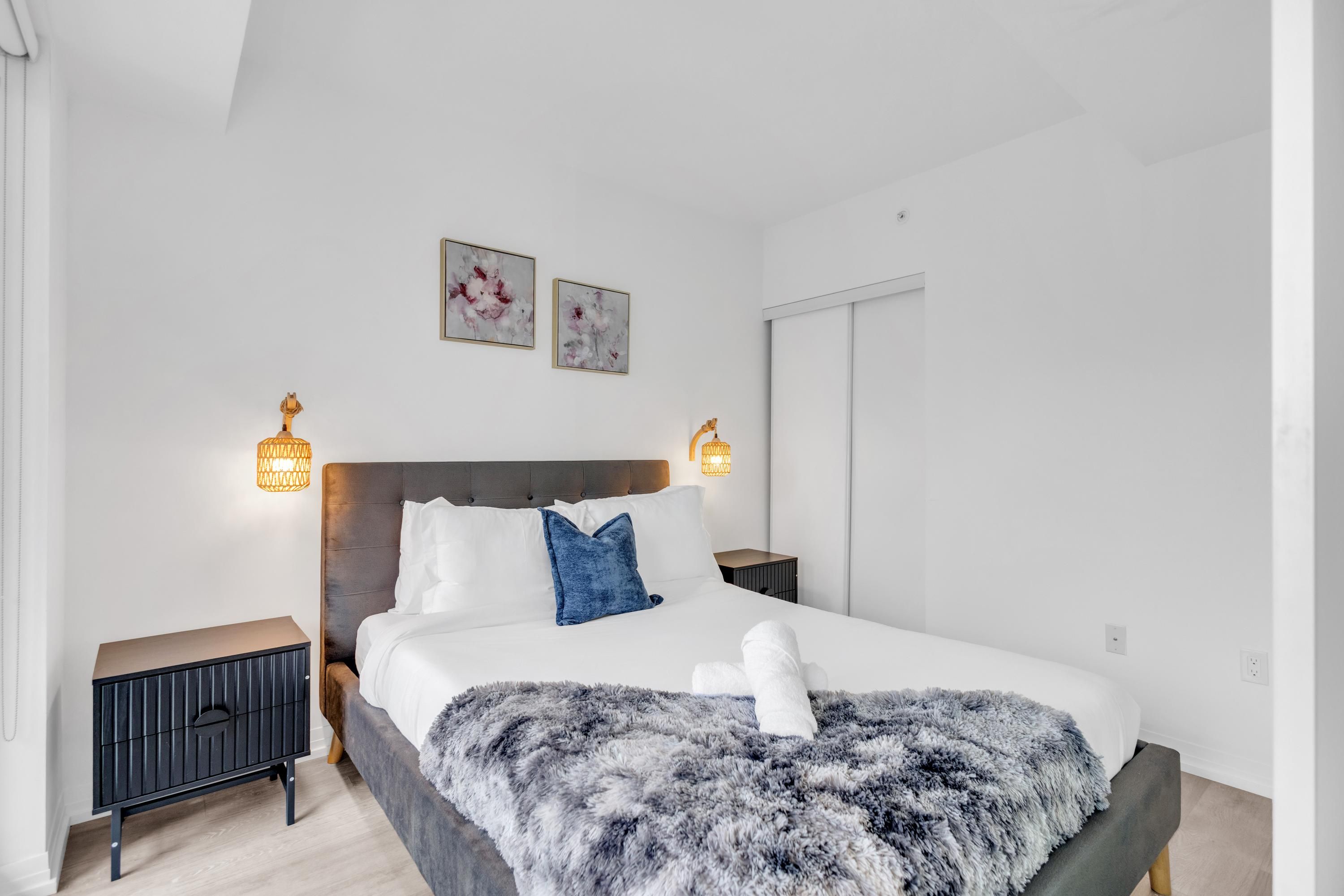 A modern bedroom with a large bed, two bedside tables, and wall-mounted lamps.