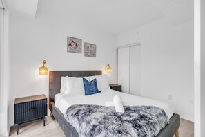 Um quarto moderno com uma cama grande, duas mesas de cabeceira e luminárias fixadas na parede.