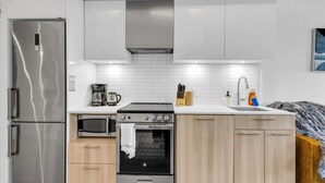A modern kitchen with stainless steel appliances, a built-in oven, and a microwave. - Downtown Suites Near Eaton Centre (Toronto)
