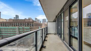 A balcony with a city view, large windows, and a concrete floor.
