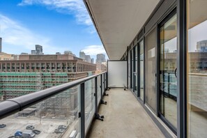 Varanda com vista para a cidade, grandes janelas e chão de concreto.