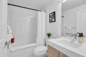 Uma casa de banho moderna com chuveiro, sanita e lavatório.