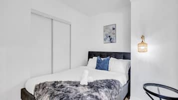 A modern bedroom with a large bed, a fluffy blanket, and a unique wall-mounted light fixture.