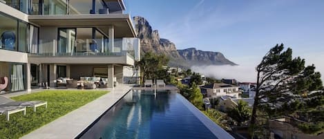 A modern hotel with a pool, balconies, and a mountain view.