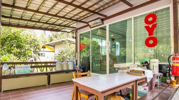 An outdoor seating area with a table and chairs, a covered roof, and a glass door with the word 'OYO' visible. - Ban Ruen Ton Num (Amphawa)
