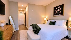 Un dormitorio con cama, mesitas de noche, un espejo y un cuadro.
