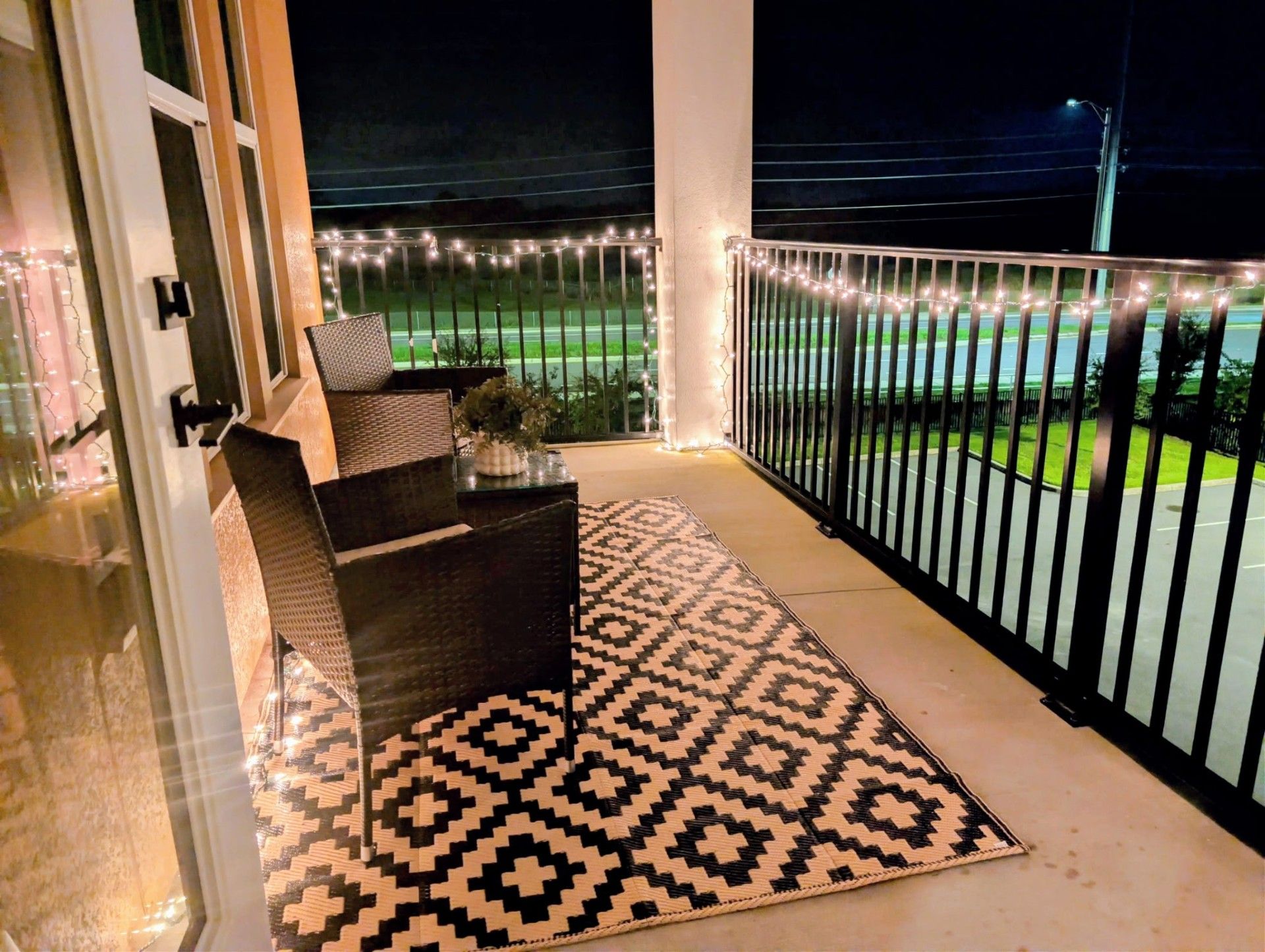 Een balkon met een gekleurd tapijt, een stoel en een tafel met een vaas.