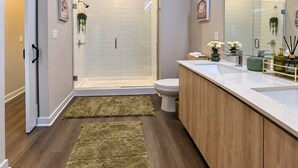 Un baño moderno con cabina de ducha de vidrio, inodoro y tocador con lavamanos.