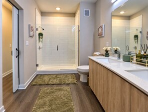 Une salle de bain moderne dotée d’une douche à parois de verre, de toilettes et d’un meuble-lavabo avec un évier.