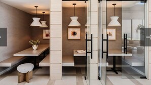 Un interior moderno con divisiones de vidrio, iluminación colgante y mobiliario minimalista.
