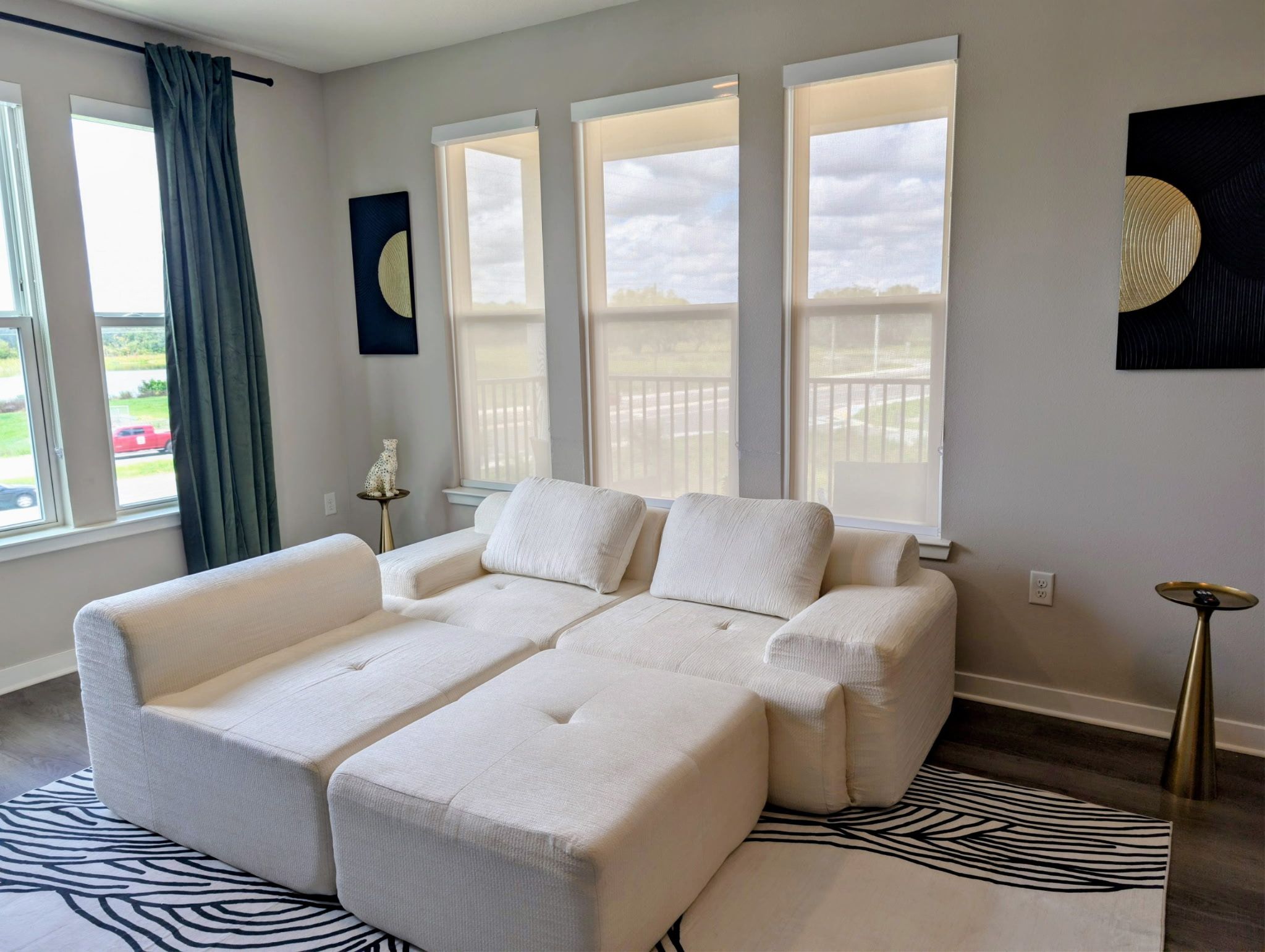 A modern living room with a sectional sofa, large windows, and a zebra-patterned rug.