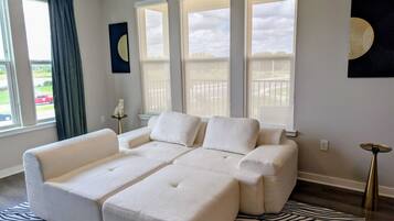 A modern living room with a sectional sofa, large windows, and a zebra-patterned rug.