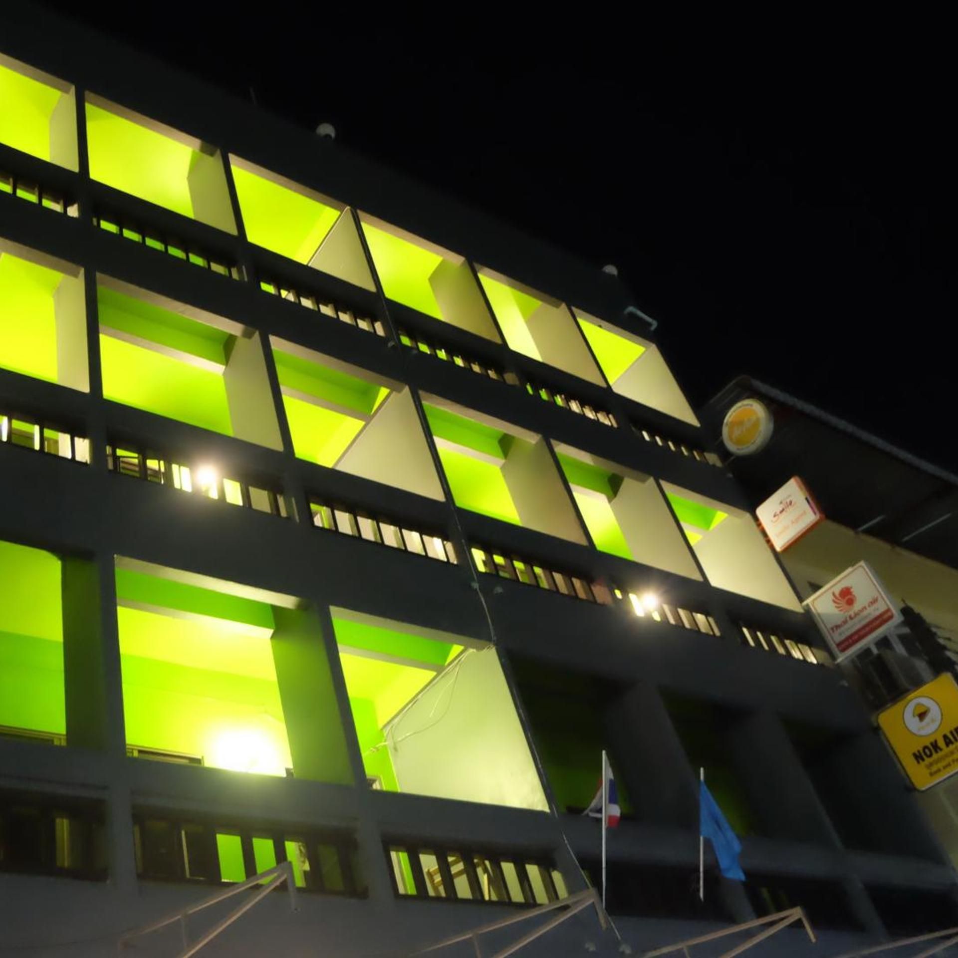 Un immeuble à plusieurs étages, doté de panneaux verts illuminés et d’une enseigne indiquant un service de la compagnie aérienne NOK Air.