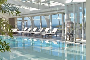 A pool area with sun loungers and a glass-enclosed structure.