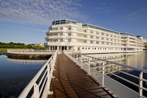 A multi-story hotel with a waterfront view, featuring a covered walkway and a boat dock.