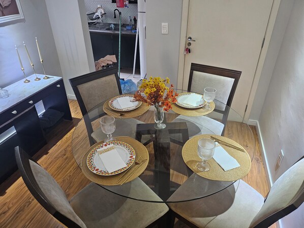 A dining table with glass top and chairs, surrounded by a kitchen area with a sink and cabinets.