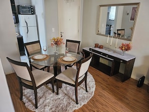 A dining area with a glass table, four chairs, and a decorative vase with flowers. - ROSE DE OLIVEIRA CESARI (Teresópolis)