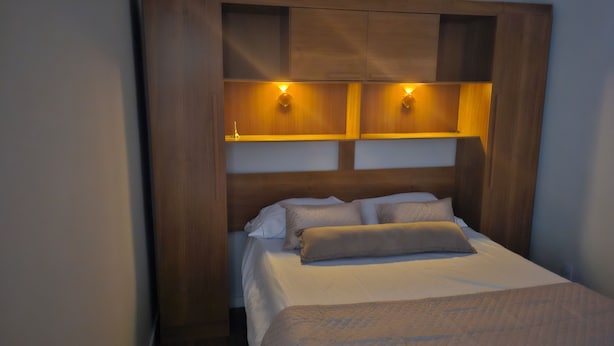 Una cama con cabecera de madera, dos lámparas de pared y una pequeña decoración de la Torre Eiffel.