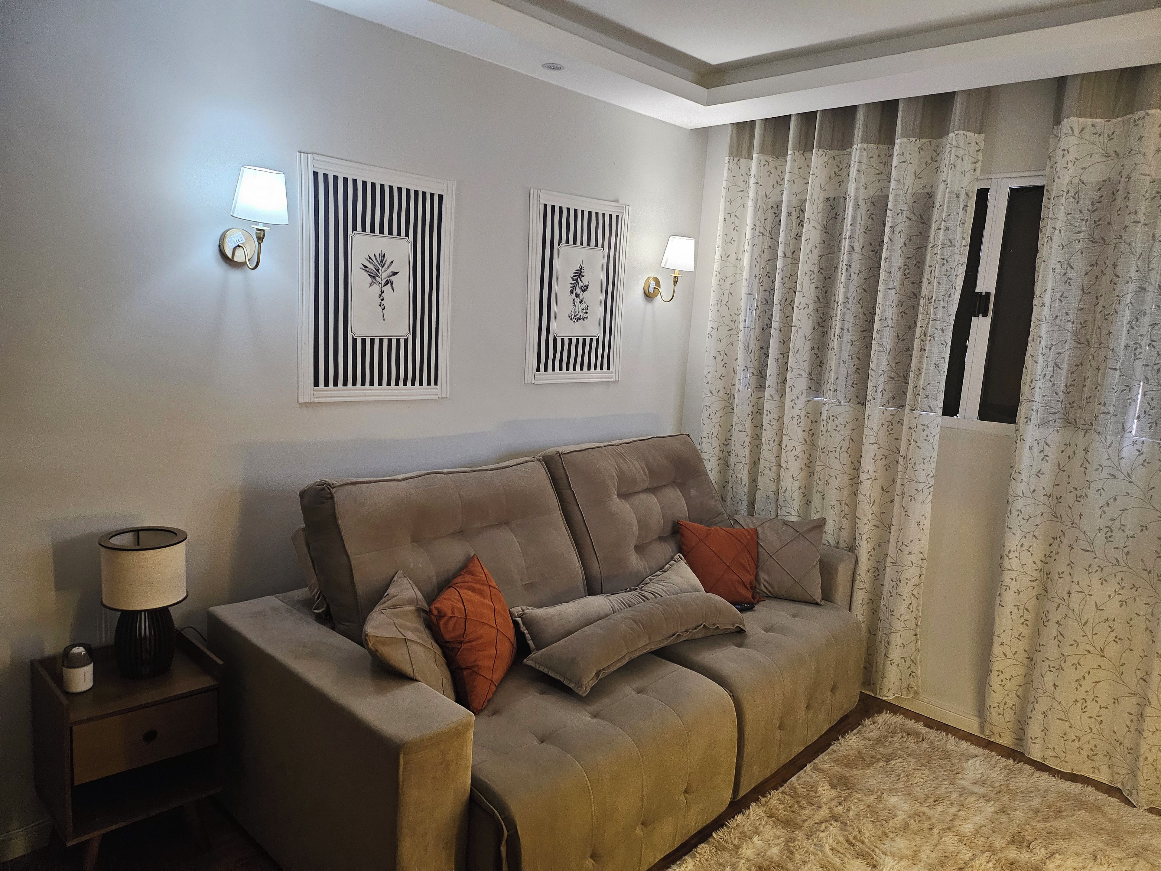 A living room with a sofa, a side table, a lamp, and two wall-mounted light fixtures.