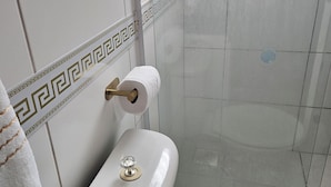 Un baño con inodoro, toalla y zona de ducha.