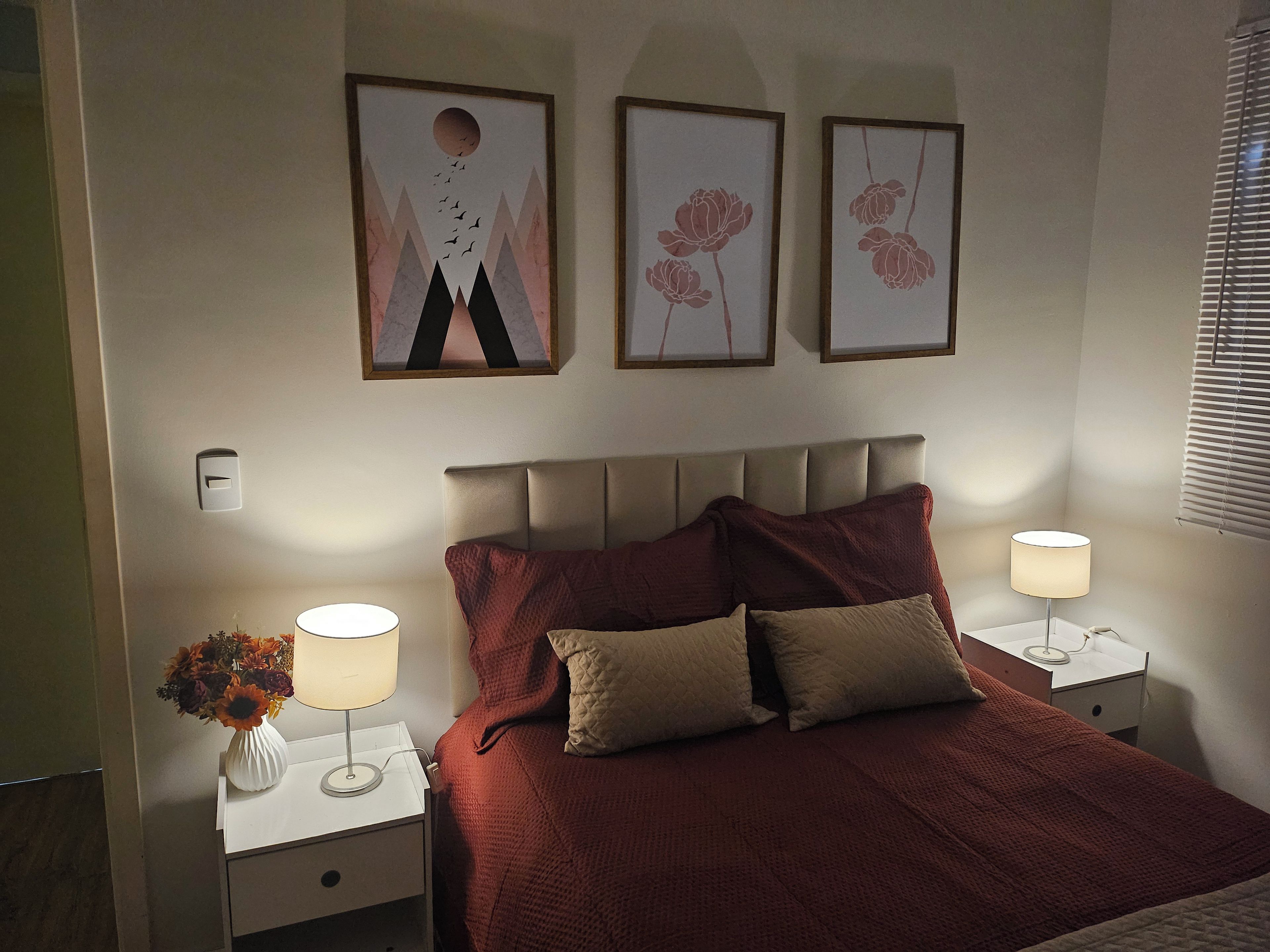Una camera da letto con un letto, due comodini, una lampada e decorazioni alle pareti.