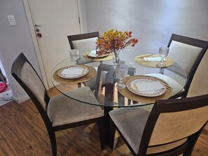A dining table with four chairs, a vase with flowers, and a glass on the table.