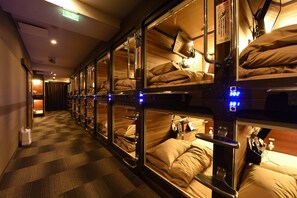 A corridor with bunk beds, each with a control panel and a headboard.