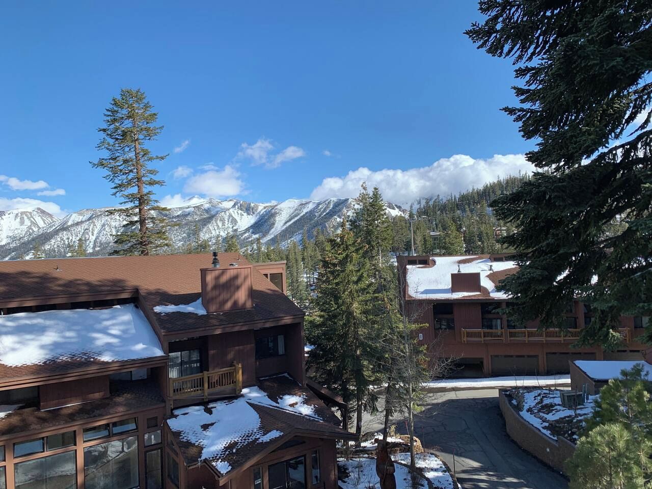 A lodge with multiple buildings, snow-covered roofs, and a mountainous backdrop.