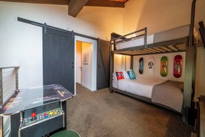 Un llit superposat amb una obra d'art mural de skateboards, una porta corredissa i una taula de futbolí.