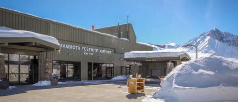 Vue extérieure de l’aéroport de Mammoth Yosemite, avec un sol enneigé et des montagnes en arrière-plan.