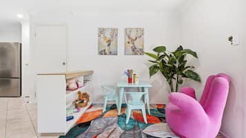 Een kleine keuken met een koelkast, een eettafel met stoelen en een kleurrijk vloerkleed.