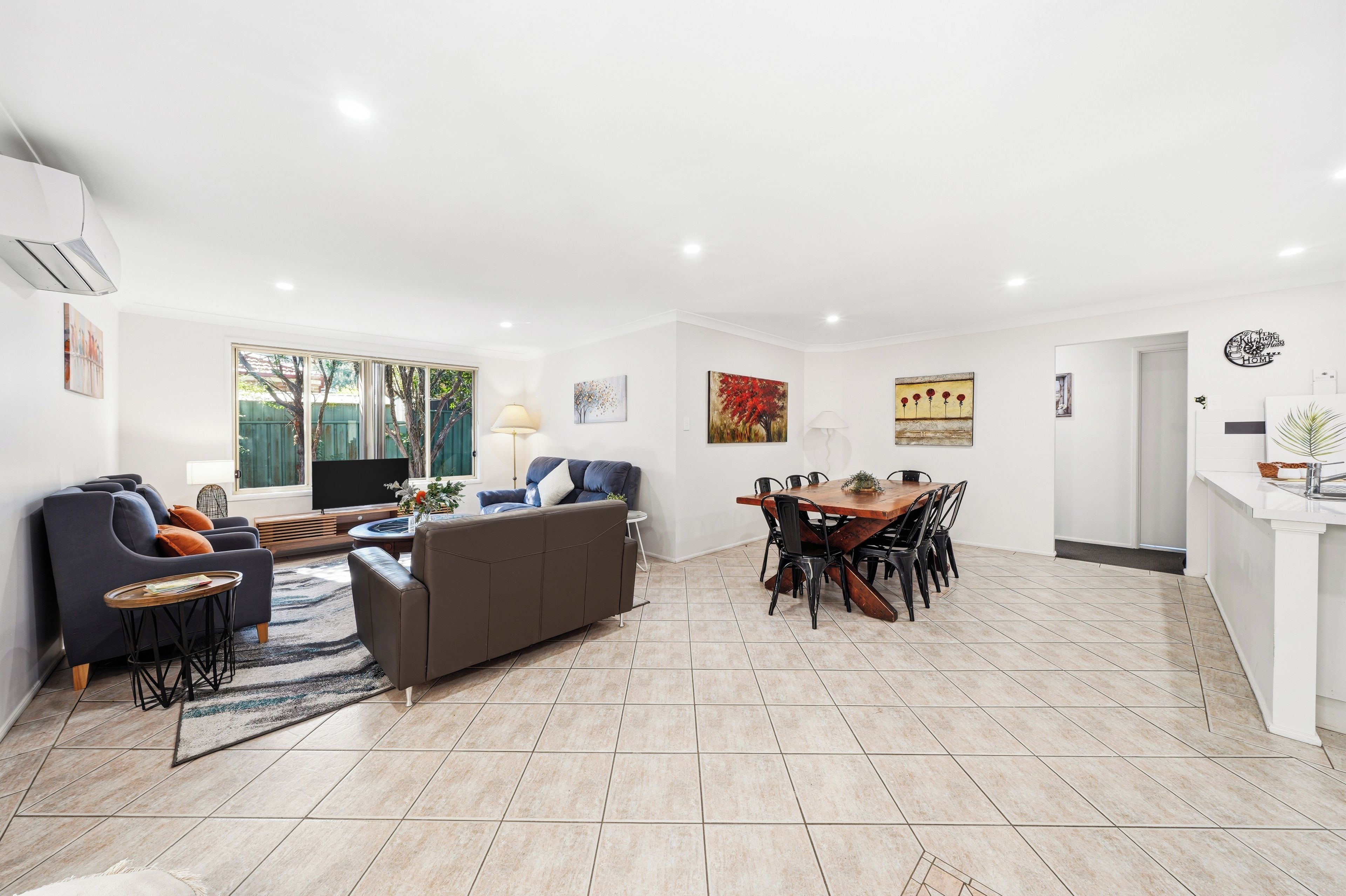 A spacious living area with a sofa, TV, and dining table.