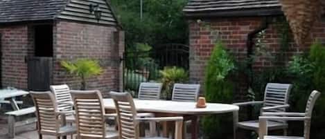Eine Terrasse im Freien mit einer Ziegelstruktur, Holzkästen und einem runden Tisch.