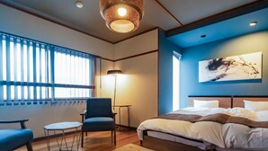 A modern hotel room with a bed, seating area, and artwork on the wall.