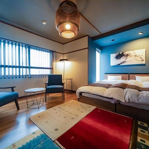 Une chambre d’hôtel moderne, équipée d’un lit, d’un coin salon et d’œuvres d’art accrochées au mur.