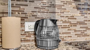 A kitchen with a stainless steel kettle on a granite countertop, a roll of paper towels, and a mosaic tile backsplash. - Harbourfront Retreat Near the Waterfront (Toronto)