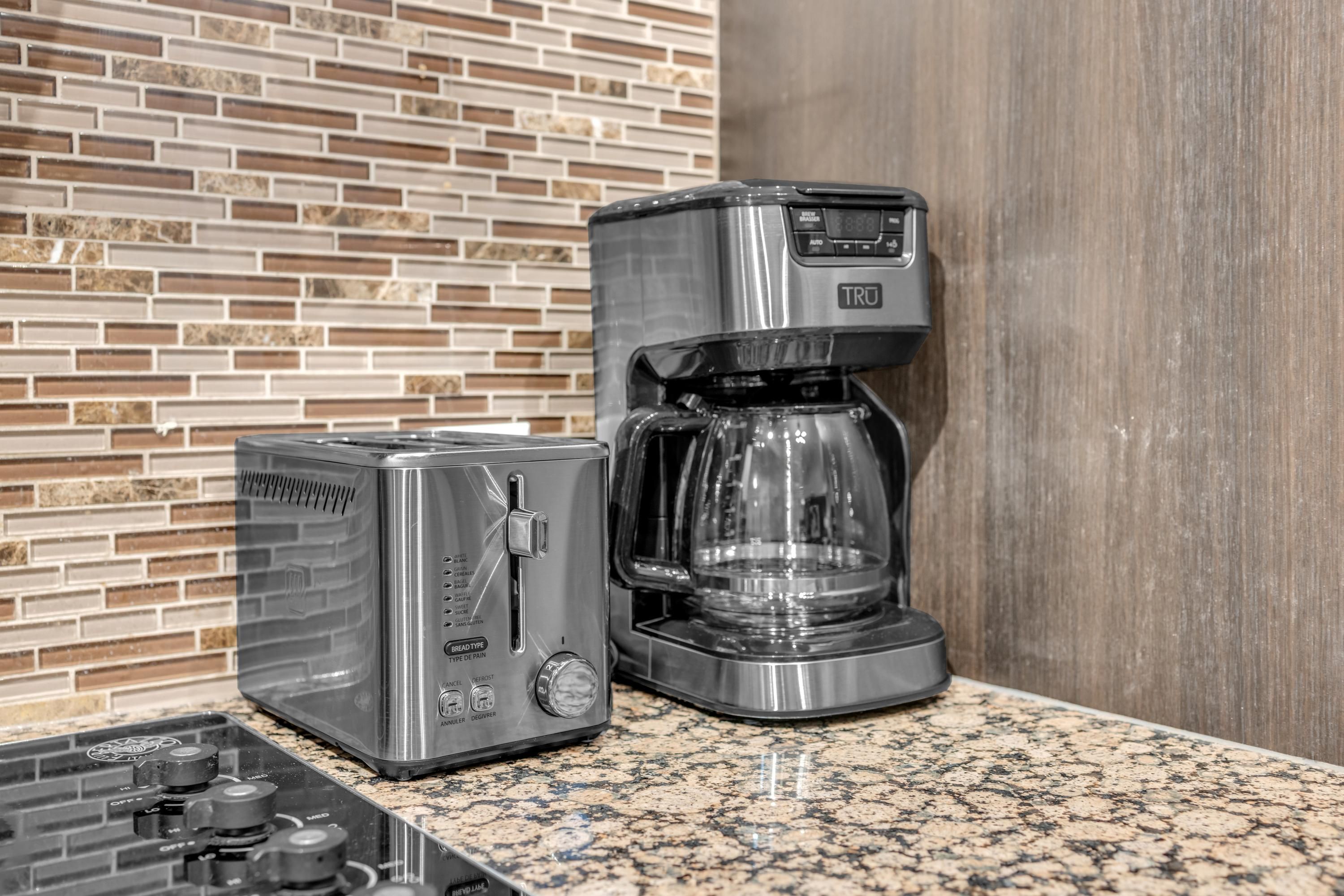Cozinha com torradeira e cafeteira em bancada de granito.