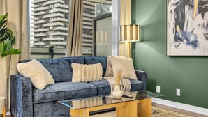 A modern living room with a blue sofa, a glass coffee table, and a green wall. - Harbourfront Retreat Near the Waterfront (Toronto)