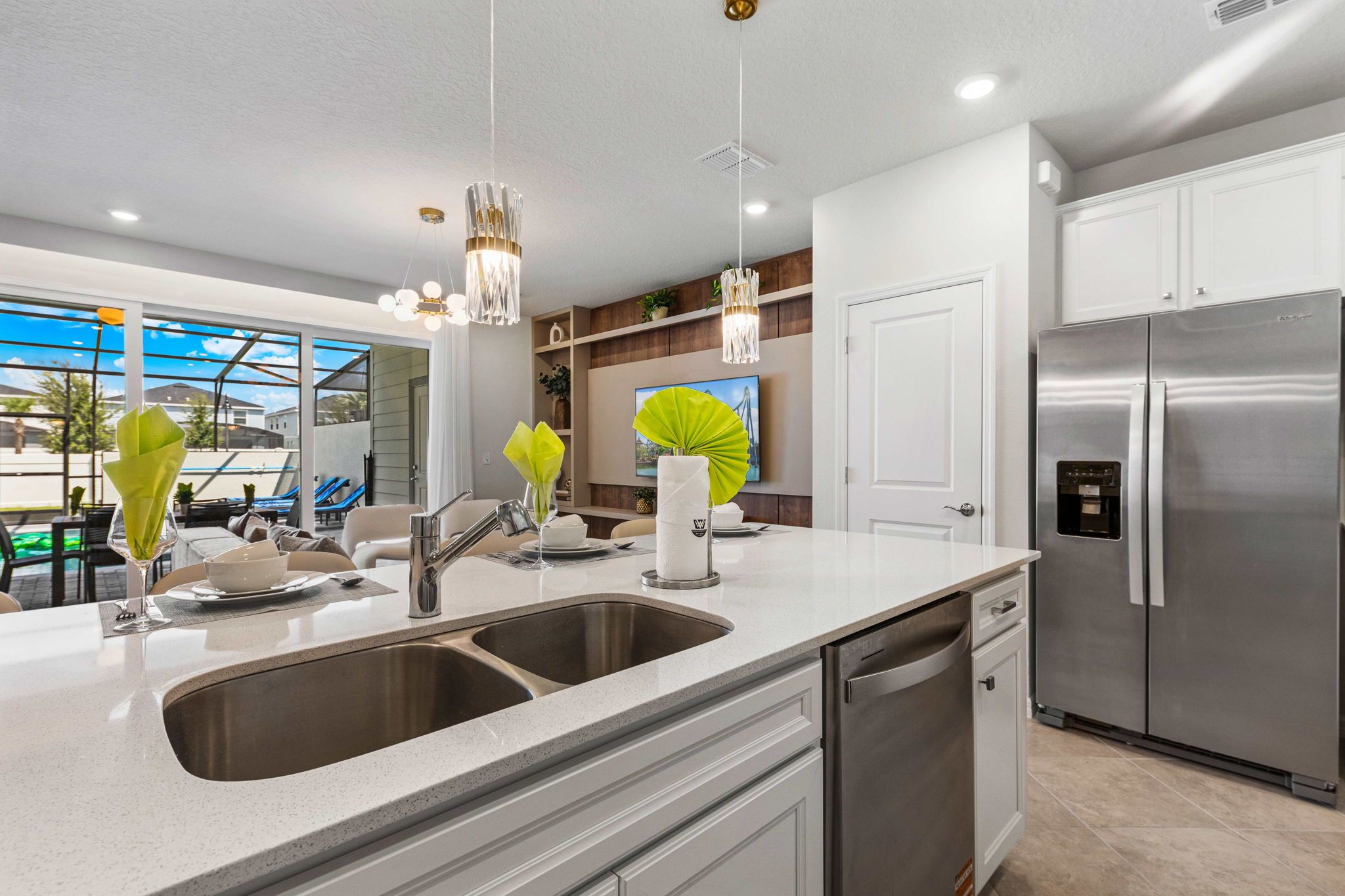 A modern kitchen with a double sink, stainless steel appliances, and pendant lighting.