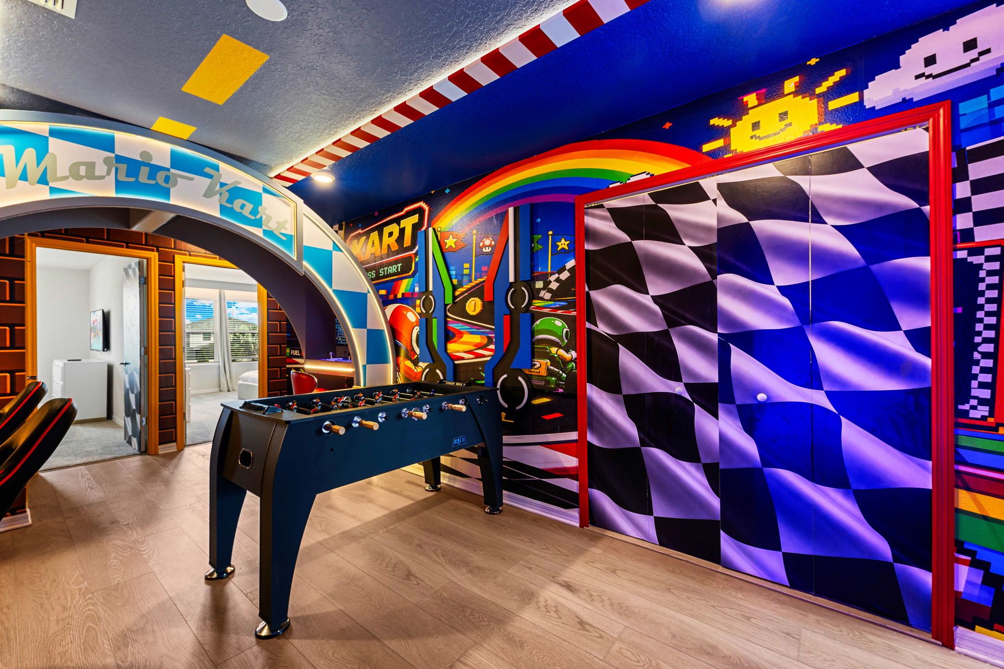 Quarto com mesa de futebol de bolso, um mural colorido e design de parede xadrez.