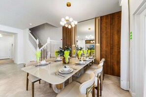 A modern dining area with a long table, chairs, and decorative vases. - Brand New | Modern 5BR with Pool & Game Room 16212 (Clermont)