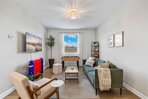 Ein Wohnzimmer mit Sofa, Sessel, Couchtisch und Fernseher, der eine schöne Aussicht zeigt.