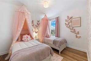 A bedroom with two beds, a canopy bed, a window with curtains, butterfly wall art, and a chandelier. - Brand New | Family 6BR Pool Spa & Game Lounge 7875 (Kissimmee)