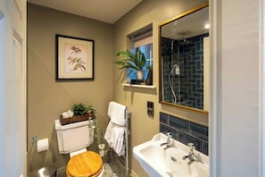 A bathroom with a toilet, sink, mirror, and a framed botanical illustration on the wall. - The Cotswold Gateway Hotel (Burford)