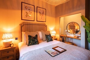 A hotel room with a bed, bedside lamps, a nightstand, a mirror, and framed artwork on the wall. - The Cotswold Gateway Hotel (Burford)
