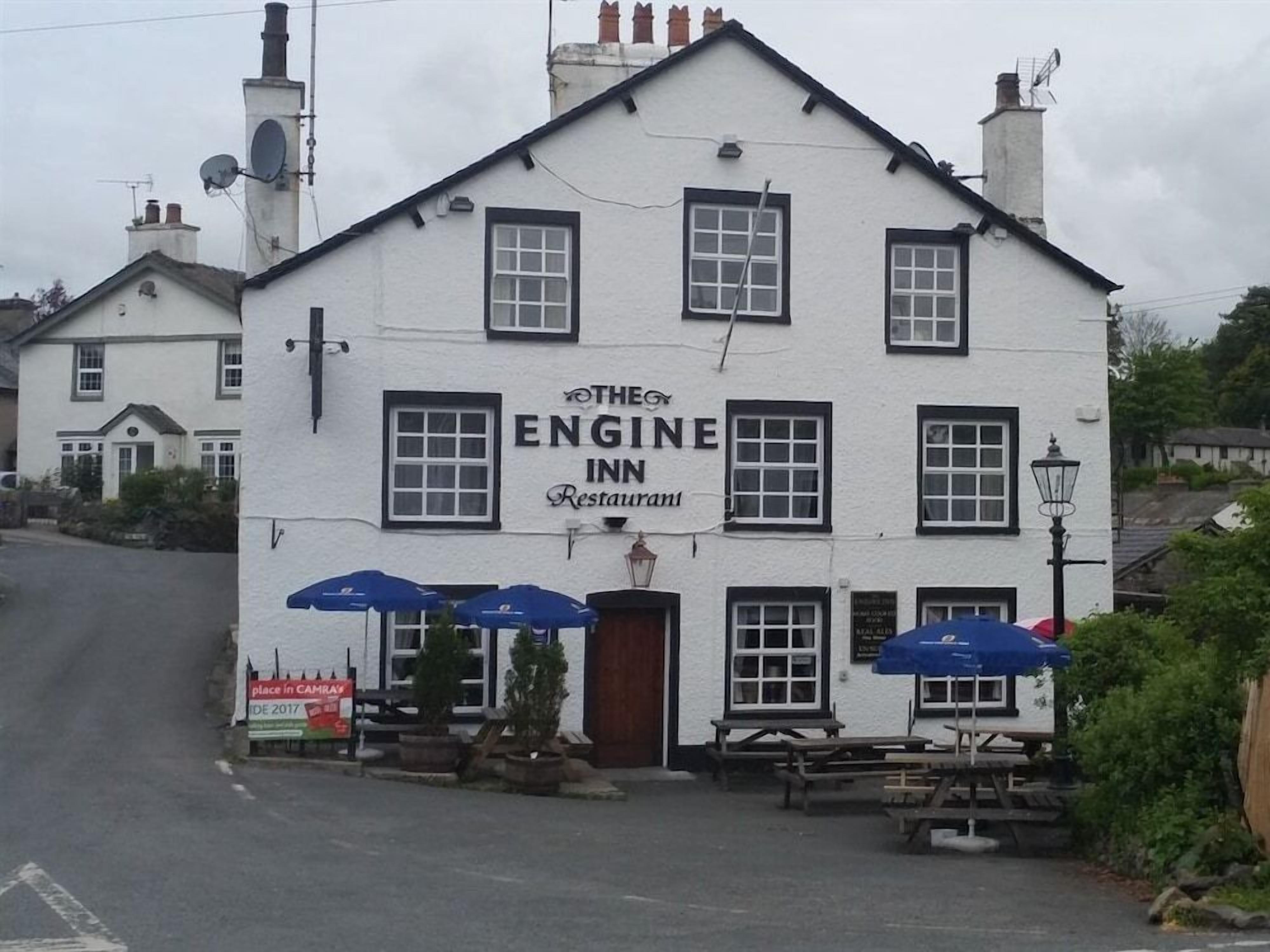 A white building with a sign reading 'The Engine Inn Restaurant' and outdoor seating with umbrellas.