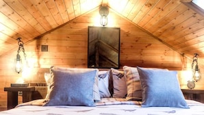A bedroom with a wooden ceiling, a bed with patterned bedding, and two bedside lamps. - Ham And Cheese Country Inn (Malton)